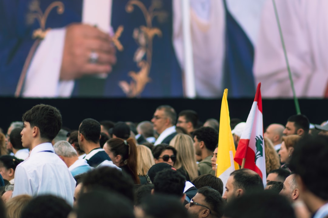 A crowd watches a large screen at an event.