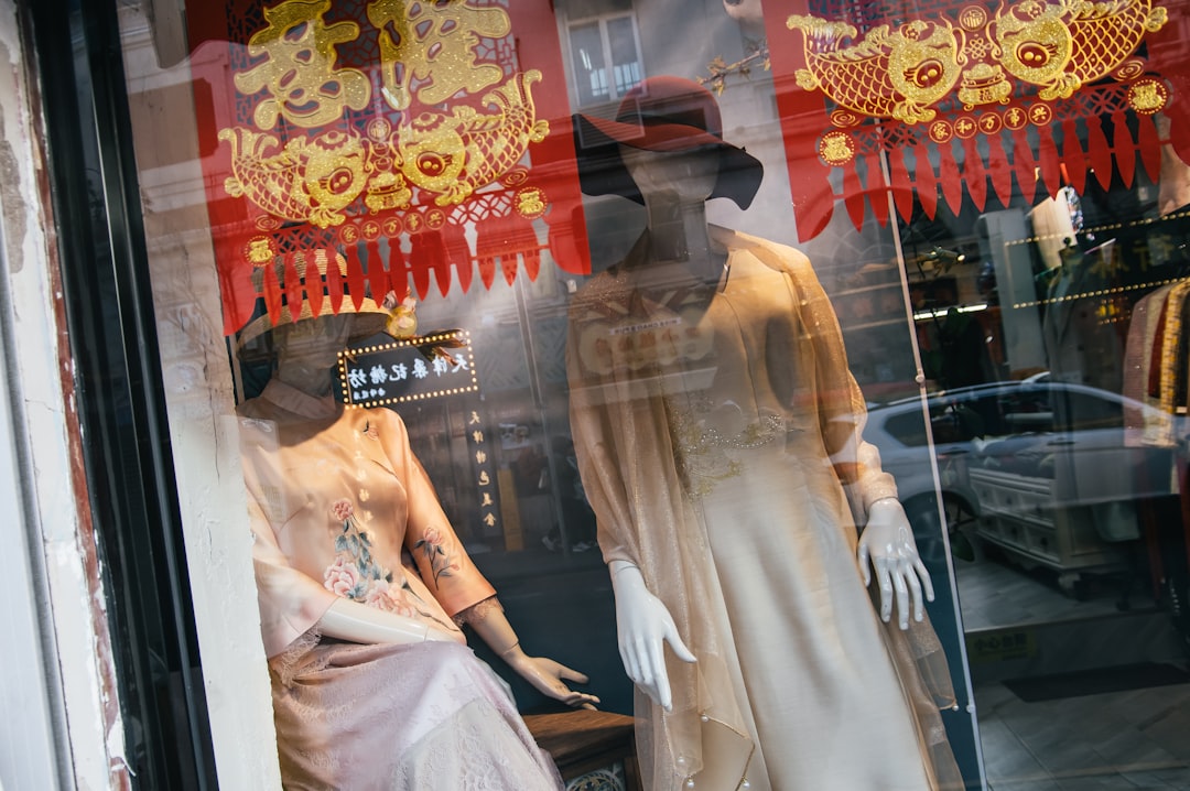 Two mannequins in a window display in front of a store