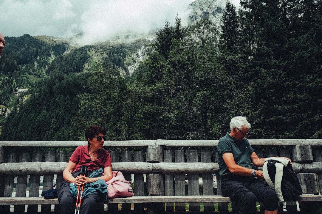 Two people resting on a bench with mountains behind them