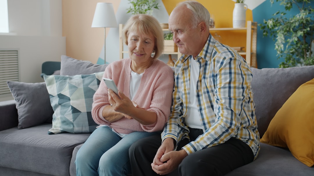 Elderly couple looking at a smartphone together on couch.